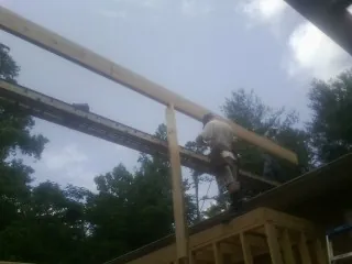 Carpenter setting a ridge beam over a new addition frame — Ice Dam Removal by Roofing Brothers in Huntly