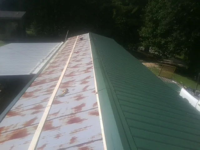 Old rusted panels beside newly installed green metal roofing — Wind Damage Roof Repair by Roofing Brothers in Huntly