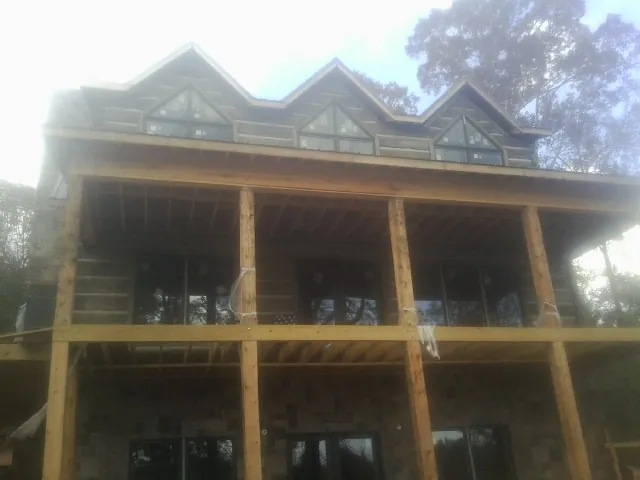 Dormers and porch framing on a large log home under construction — Roof Coating work by our crew in Huntly