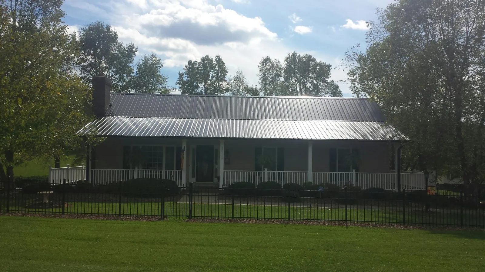 Gray metal roof on a brick ranch with a full width front porch — Gutter Guard Installation work by our crew in Huntly